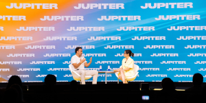 Two people speaking to each other on stage in frnt of a live audience at Jupiter Festival Miami.